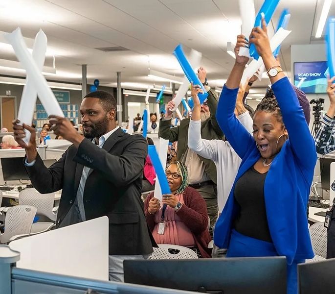 Spectrum employees celebrating an achievement in the office with balloons