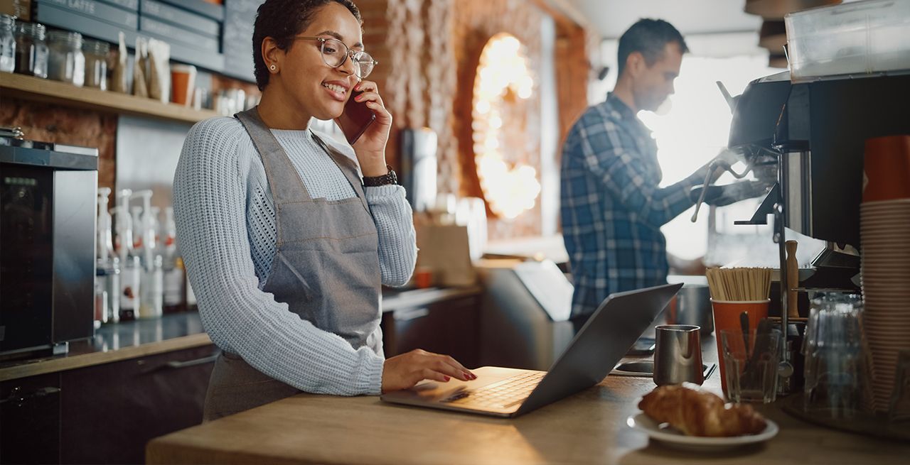 Latina small business owner talking on her mobile phone in her coffee shop