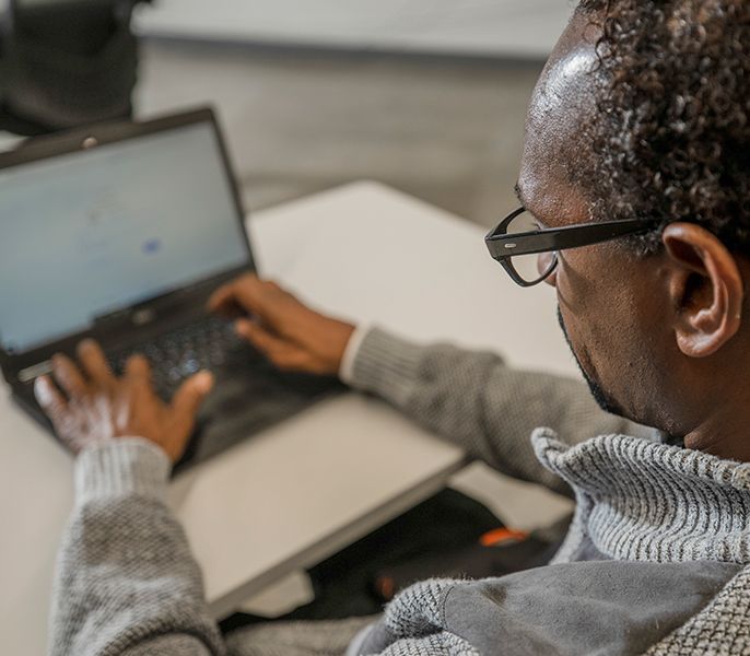 Elderly man learning on a laptop in a computer lab