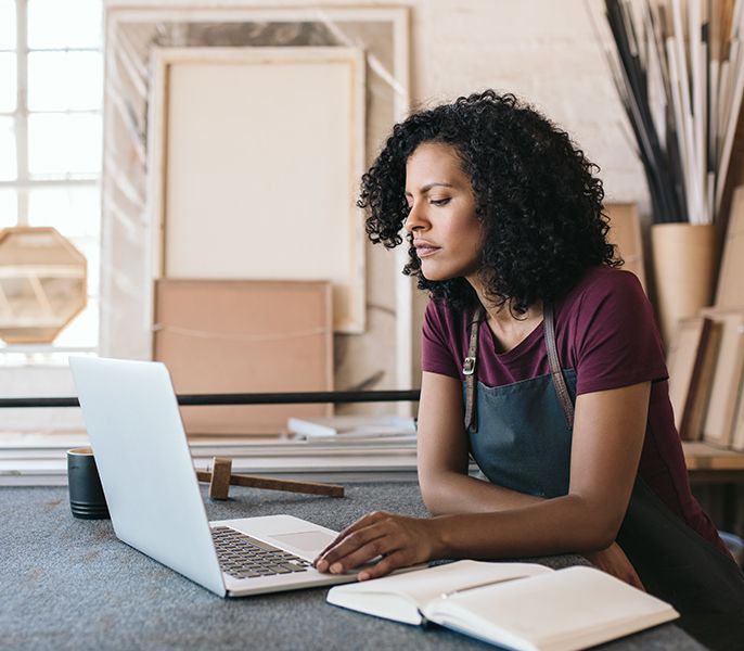 Female minority small business owner working on laptop in her office